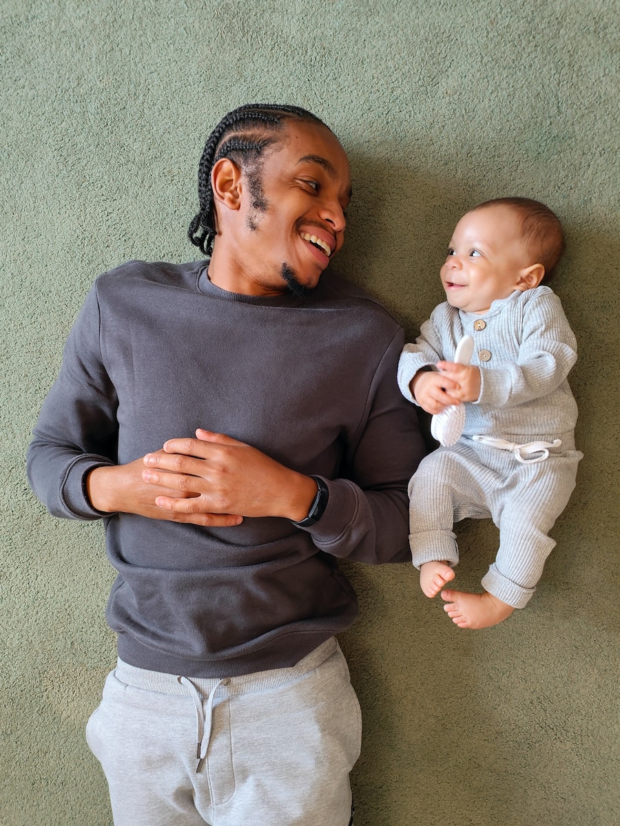 father laying on floor next to baby